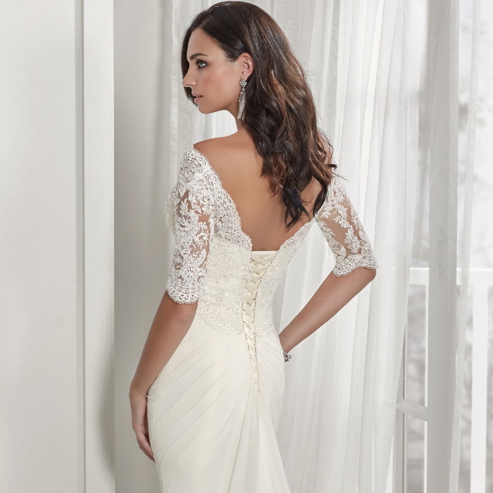 Back profile of a brunette model in an ivory wedding dress with a corset back and ¾ lace sleeves